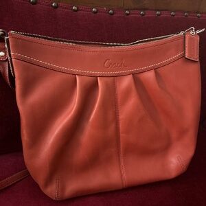 Dark orange leather coach bag with two straps.